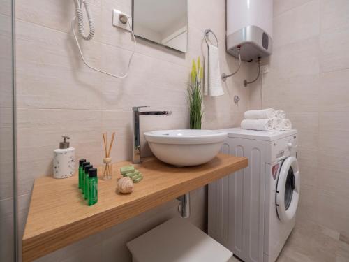 a bathroom with a sink and a washing machine at Apartments Garden Azure Budva in Budva