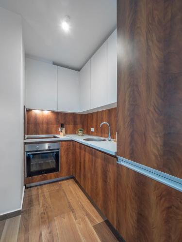 a kitchen with wooden cabinets and a sink at Apartments Garden Azure Budva in Budva