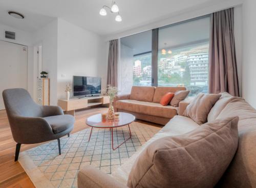 a living room with a couch and a chair at Apartments Garden Azure Budva in Budva