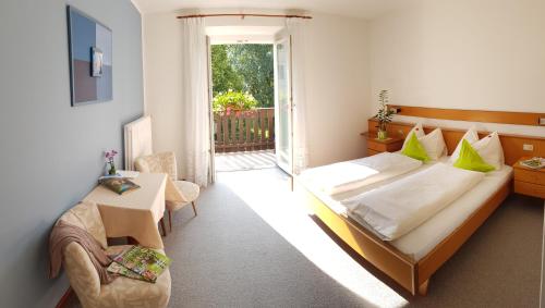 a bedroom with a large bed and a balcony at Pension Gartscheid in Lana