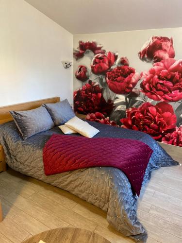 ein Schlafzimmer mit einem Bett mit roten Blumen an der Wand in der Unterkunft PIVOINE Chambre d hotes in Fralignes