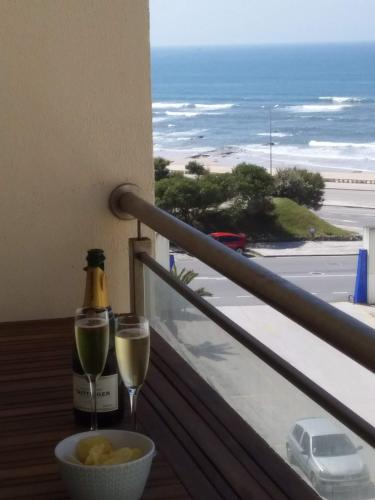 a bottle of wine and two glasses on a balcony at Atlantic Beach-side Apartment in Figueira da Foz
