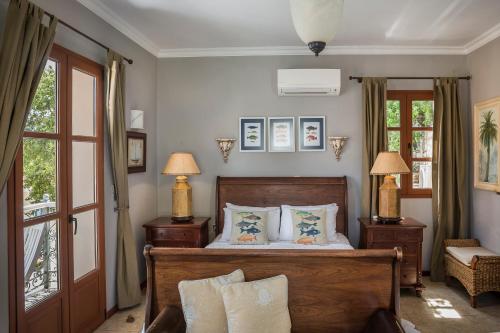 a bedroom with a bed with two lamps and windows at Faros Suites (Adults Only) in Fiskardho