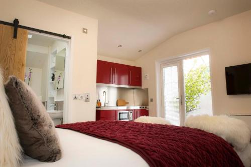 a bedroom with a bed with red cabinets and a kitchen at Pear Tree Cottage in Cullen