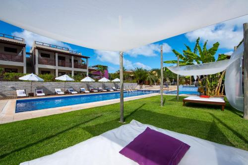 a bed under a white canopy next to a swimming pool at Pipa Beleza Spa Resort in Pipa