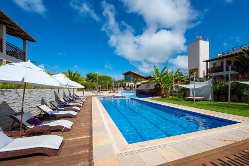 a pool with lounge chairs and umbrellas next to a building at Pipa Beleza Spa Resort in Pipa