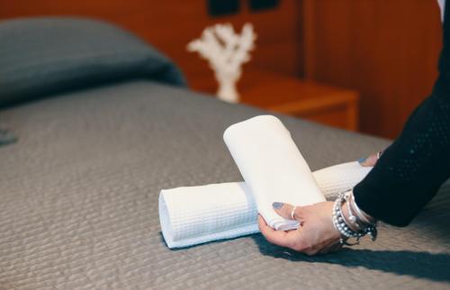 a person holding a roll of toilet paper on a bed at Hotel Almas in Capaccio-Paestum