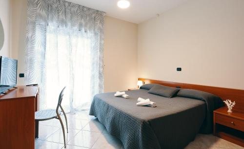 a bedroom with a bed with two towels on it at Hotel Almas in Capaccio-Paestum