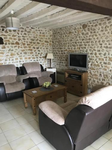 un salon avec des canapés et une télévision à écran plat dans l'établissement Gite Regal, à Suaux