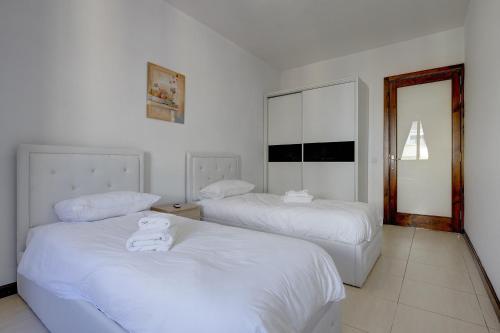 - une chambre avec 2 lits avec des draps blancs et un ours en peluche sur le dessus dans l'établissement Modern 3 Bedroom Apartment in Central Sliema, à Sliema