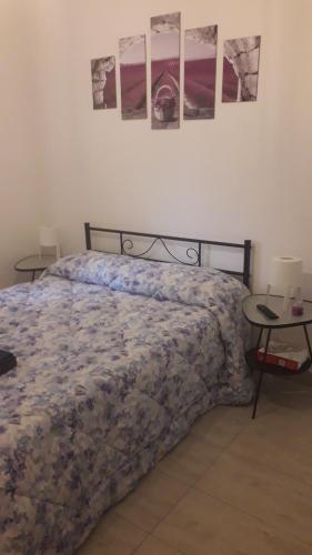um quarto com uma cama e duas mesas com quadros na parede em b&b Il Sorriso em Pozzilli