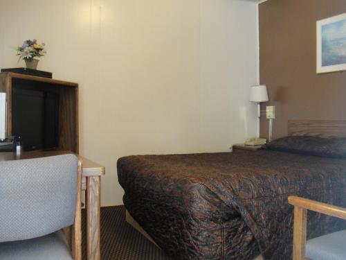 una camera d'albergo con letto, scrivania e sedia di California Motel a California