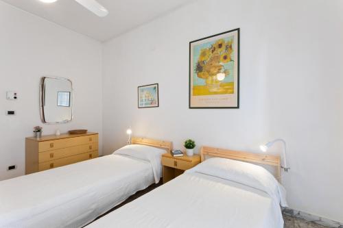 two beds in a room with white walls at Aci Castello Seaview Apartment with Parking in Aci Castello