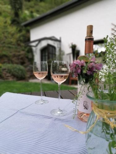two wine glasses sitting on a table with a bottle of wine at BrexHäuschen - Urlaub im Grünen in Höhr-Grenzhausen