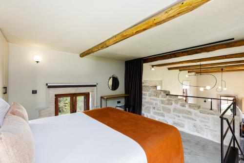 a bedroom with a white bed and a stone wall at Villa Rossa in Arkhondikí