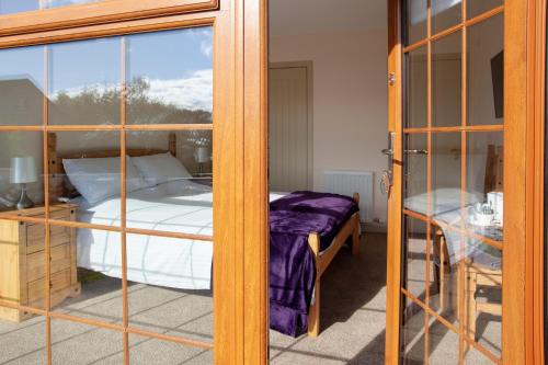 a bedroom with a bed through a glass door at Balintore Inn in Balintore