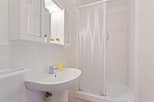a white bathroom with a sink and a shower at Aci Castello Seaview Apartment with Parking in Aci Castello