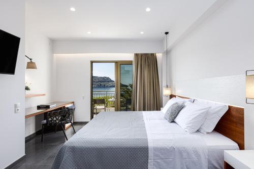 a bedroom with a bed and a desk and a window at Artemis Exclusive Double Sea View Adults Only in Plakias
