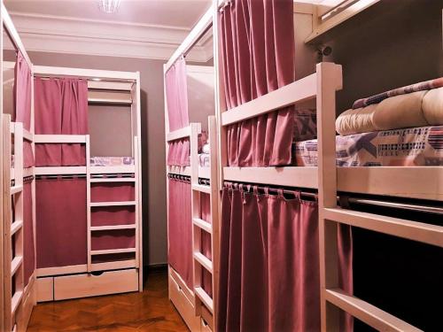 a room with three bunk beds with pink curtains at Bulgakoff in Kyiv