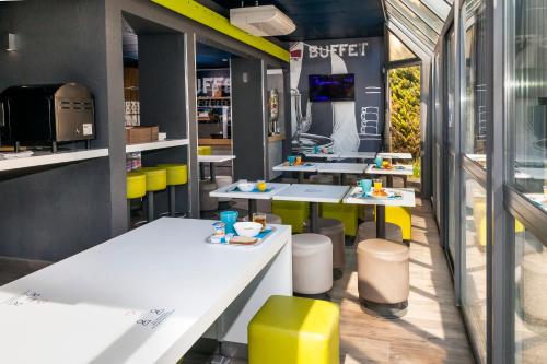 a fast food restaurant with white tables and yellow stools at ibis budget Antony Massy rénové 2024 in Antony