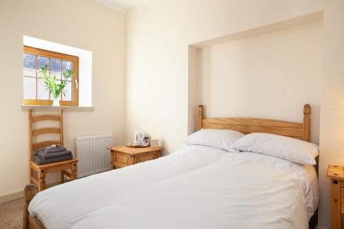 a bedroom with a bed with white sheets and a window at Balintore Inn in Balintore
