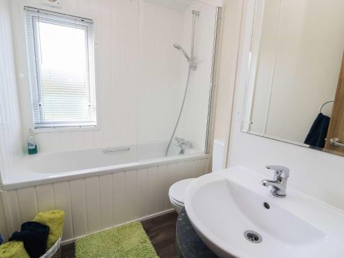 a white bathroom with a sink and a bath tub at The Potting Shed in New Quay