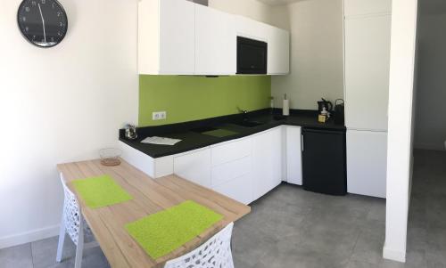 uma cozinha com armários brancos e uma mesa com uma parede verde em Cassis Lodges em Cassis