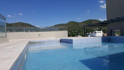 a swimming pool with blue water in a building at Departamento céntrico, pileta cochera moderno y lujoso in Villa Carlos Paz