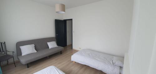 een woonkamer met een bank en een bed bij LFA La petite maison du coin in Flémalle-Grande