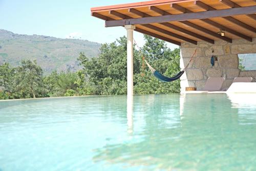 a swimming pool with a hammock in the water at Quinta de S. Cipriano in Resende