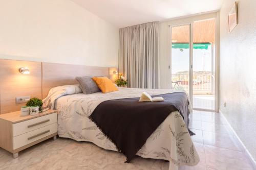 a bedroom with a bed with a book on it at Homes&Go Bell Racó Confort III in La Pineda