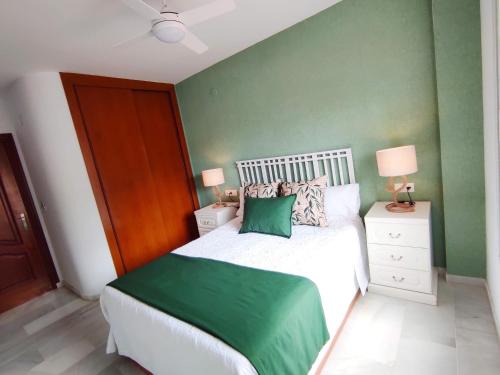 een slaapkamer met een wit bed en een groene muur bij Apartamento Oasis La Herradura in La Herradura