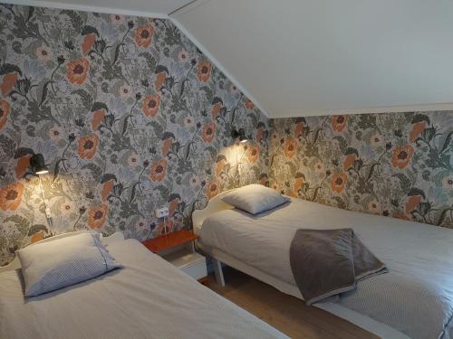 a bedroom with two beds and a wall with flowers at Vandrarhemmet Tallbacka/Ängelsberg Hostel in Ängelsberg