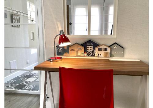 a desk with a red chair and a house on it at La Cabine De La Baie in Saint-Pair-sur-Mer