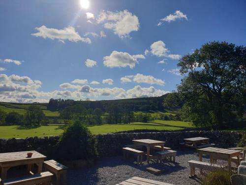 a group of picnic tables in front of a green field at The New Inn in Skipton