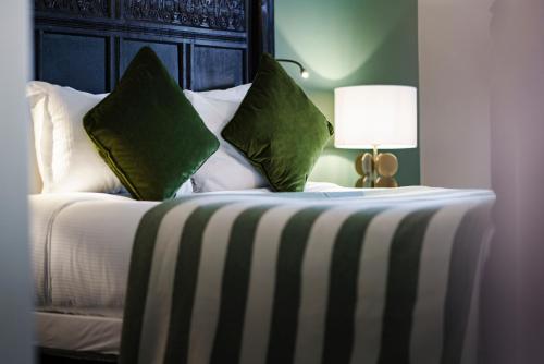 a bedroom with a bed with green and white pillows at The White Hart Hotel in Kingston upon Thames