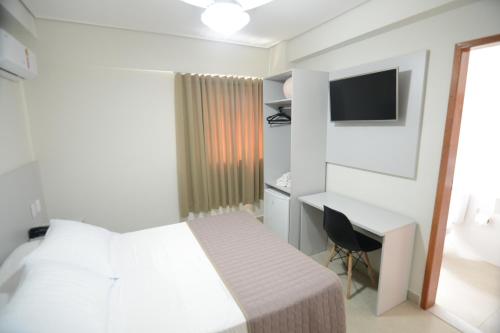 a bedroom with a bed and a desk and a television at Hotel Milenio in Ponte Nova