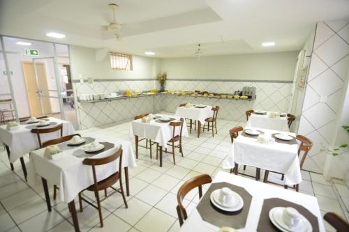 a restaurant with white tables and chairs and a counter at Hotel Milenio in Ponte Nova