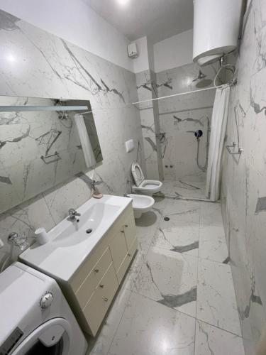 Baño blanco con lavabo y aseo en Gjiri Lalzit Apartment, en Durrës