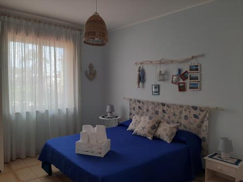 1 dormitorio con cama con sábanas azules y ventana en Al giardino Sant'Anna, en Mascali