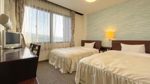a hotel room with two beds and a television at Hotel Kawaguchiko in Fujikawaguchiko