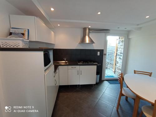 une cuisine avec des armoires blanches, une table et une fenêtre dans l'établissement Le casino larmor, à Plougastel-Daoulas