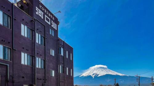 a snow covered mountain in the distance behind a building at Hotel Kawaguchiko in Fujikawaguchiko