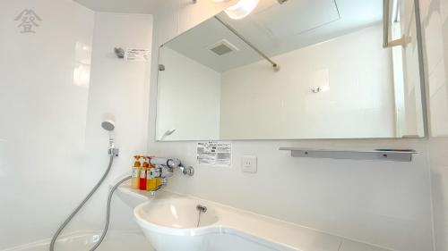 a white bathroom with a sink and a mirror at Hotel Kawaguchiko in Fujikawaguchiko