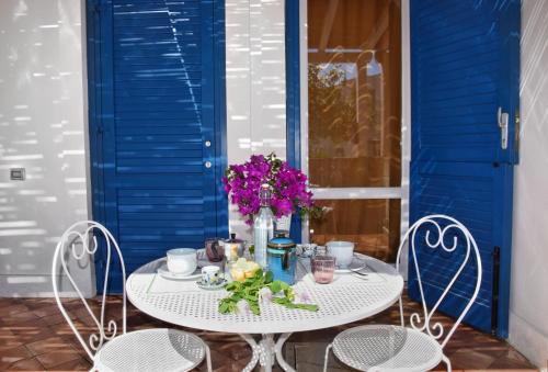 Favignana Casa Vacanza Orsola في فافينانا: طاولة مع كرسيين و مزهرية من الزهور