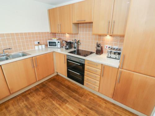 a small kitchen with wooden cabinets and a sink at Seashells in Tenby