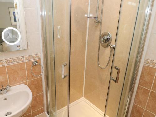 a shower with a glass door next to a sink at Seashells in Tenby