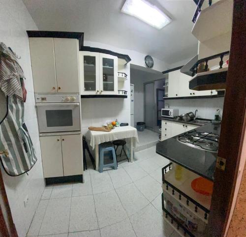 a kitchen with white cabinets and a table in it at Apartamento Turístico en el centro in Tarragona
