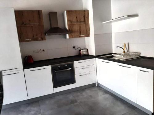 a kitchen with white cabinets and black counter tops at St Julians Bay Sea Front Apartments in St Julian's