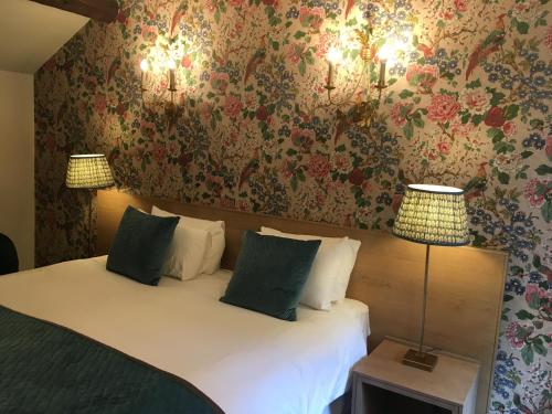 a bedroom with a bed with two lamps and floral wallpaper at The Swan at Tarporley in Tarporley